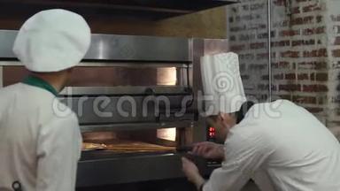 两位厨师将生披萨放入热比萨饼烤箱